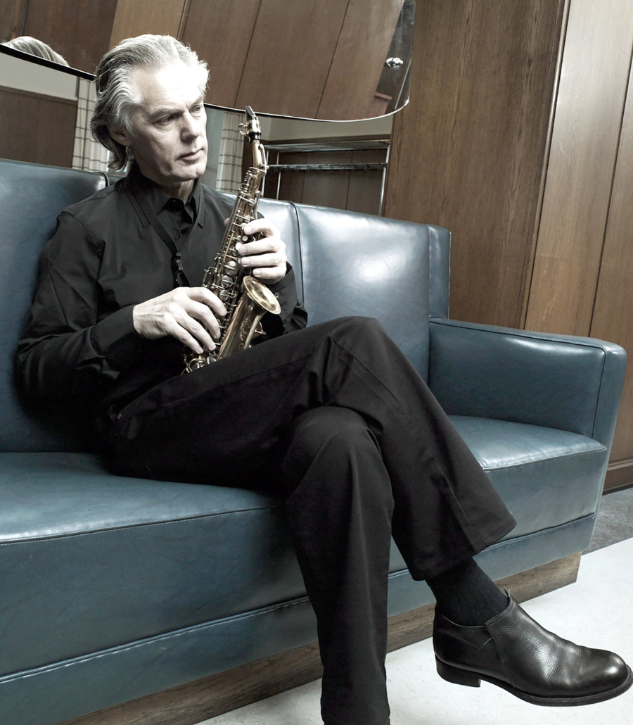 Der Musiker Jan Garbarek sitzt auf einer Couch.