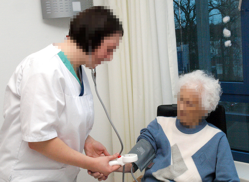 Ein Pflegerin betreut eine alte Dame.
