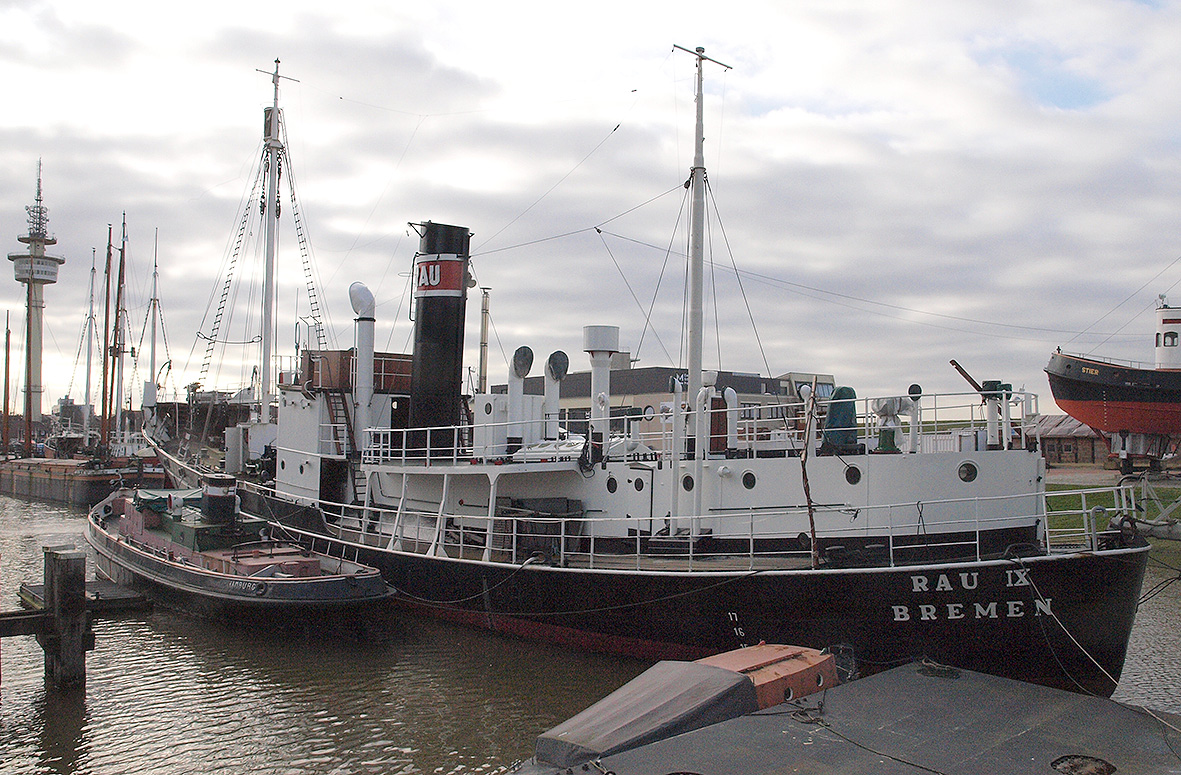 Ein Walfangschiff und ein Binnenschlepper liegen im Hafen.