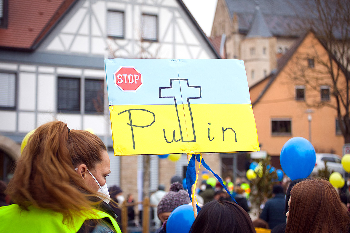 Eine Demonstrantin hält ein Anti-Putin-Schild hoch.