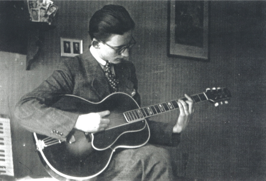 Ein junger Mann in Swing-Kleidung spielt Gitarre.