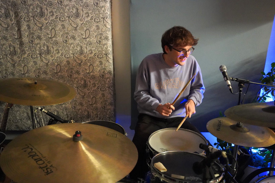 Ein junger Mann sitzt hinter einem Schlagzeug und spielt. 