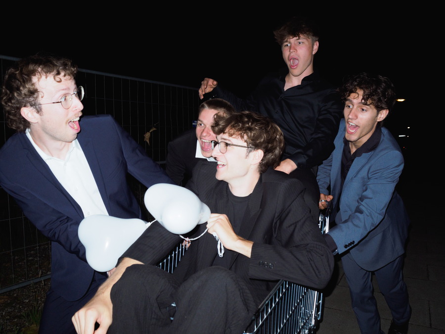 Fünf Jungs haben Spaß im Dunkeln mit einem Einkaufswagen.