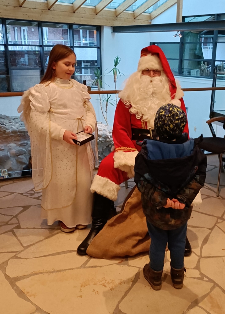 Der Weihnachtsmann und der Engel Schneeflöckchen hören sich Wünsche und Gedichte an.