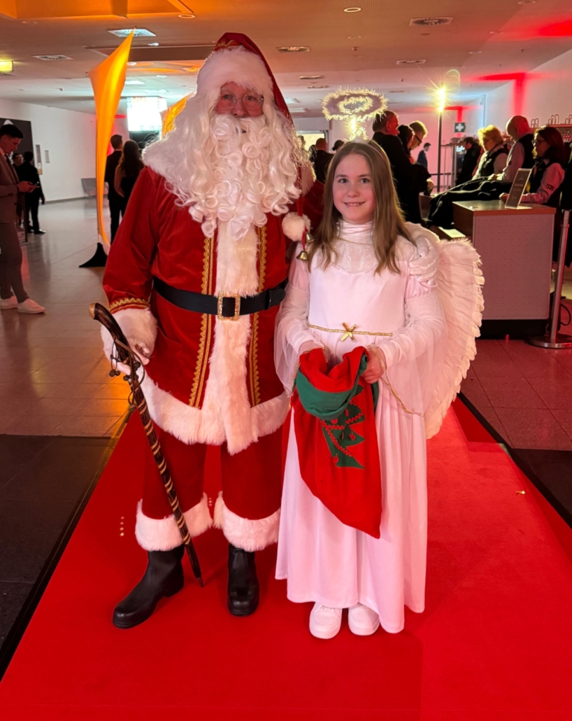 Der Weihnachtsmann und der Engel Schneeflöckchen auf dem roten Teppich.