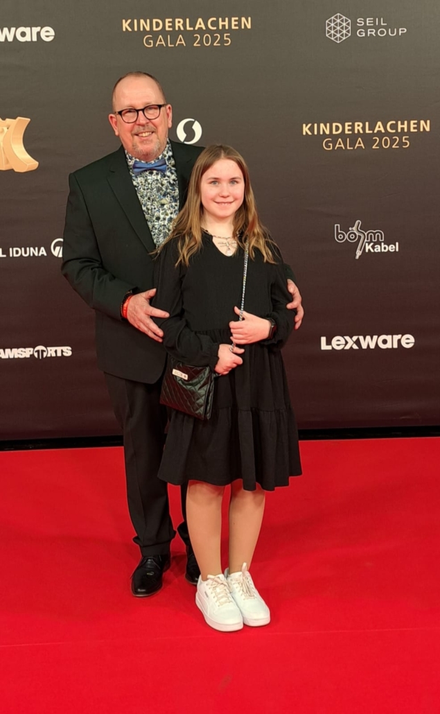 Der Weihnachtsmann und der Engel Schneeflöckchen - beide in zivil - auf dem roten Teppich.